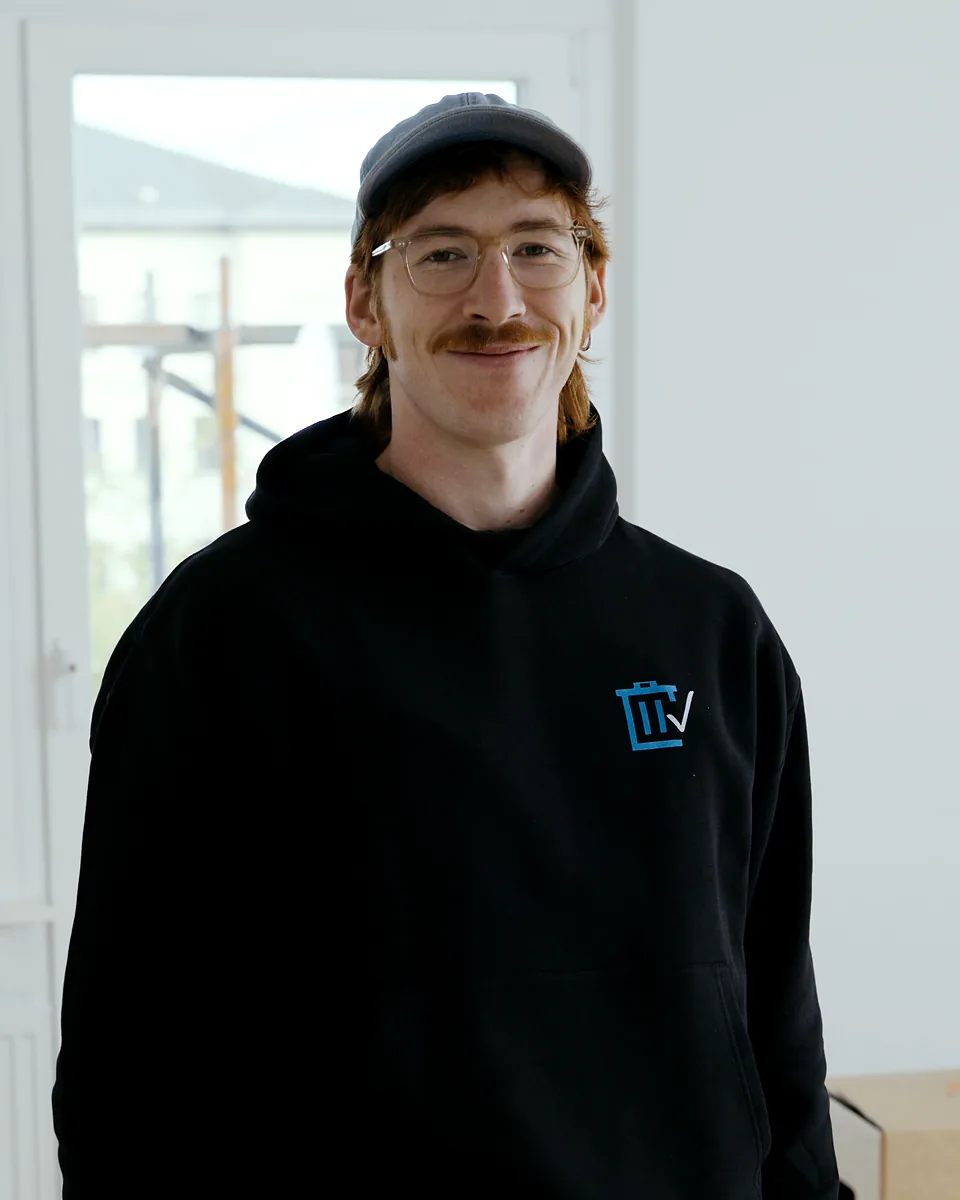 Luis Scholz von Sorglos Entrümpeln mit Kappe und Brille im schwarzen Kapuzenpullover mit Sorglos-Logo