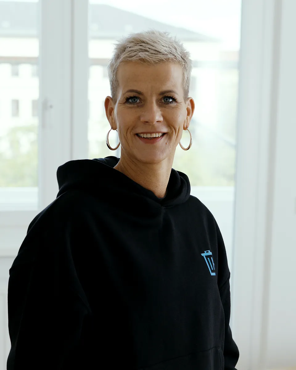 Marleen Wötzel von Sorglos Entrümpeln mit kurzen hellen Haaren im schwarzen Kapuzenpullover mit Sorglos-Logo