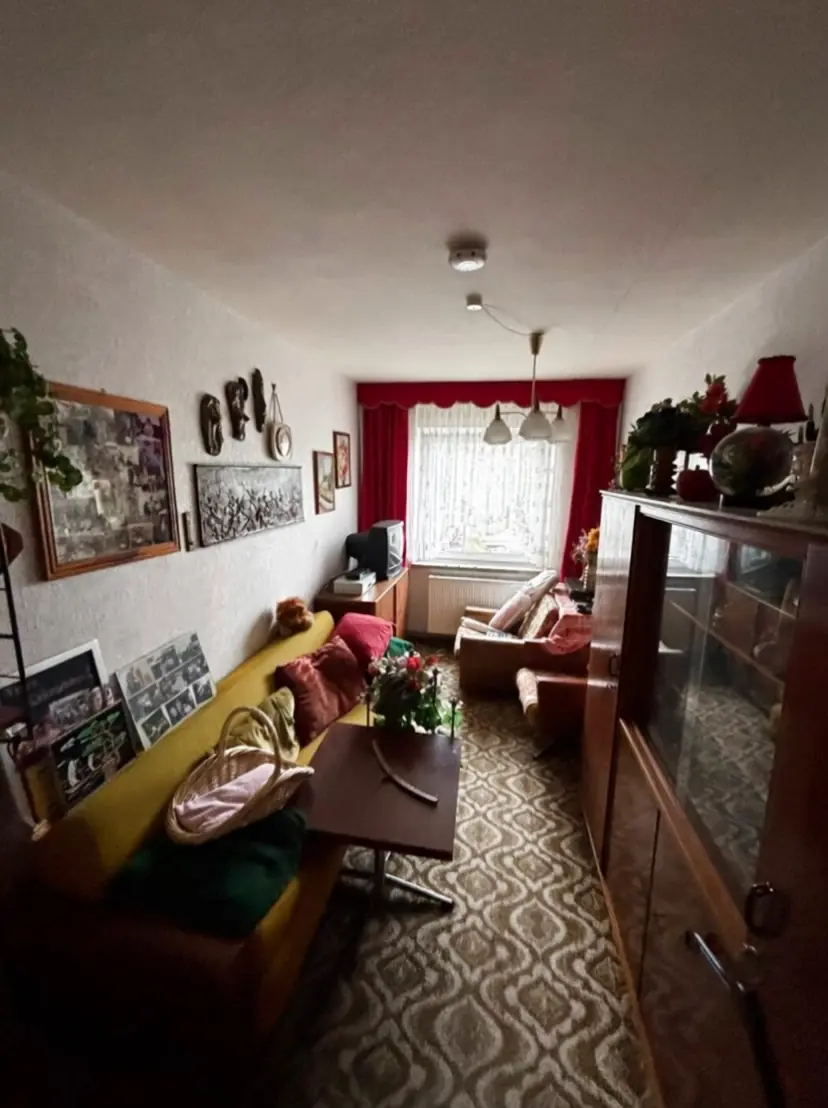 Wohnzimmer vor der Räumung: Sofa, Schrankwand und Kisten füllen den Raum
