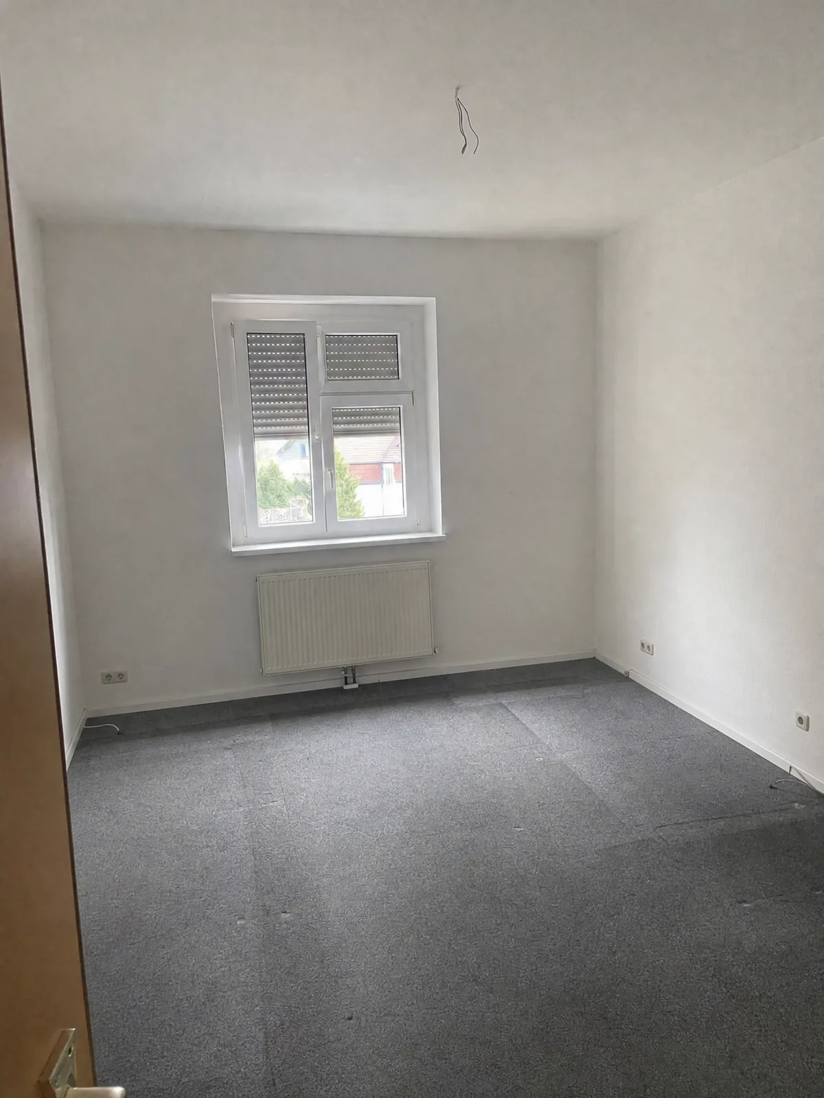 Derselbe Büroraum nach der Auflösung: leere Teppichfläche, nichts steht mehr, Fenster und Heizkörper frei