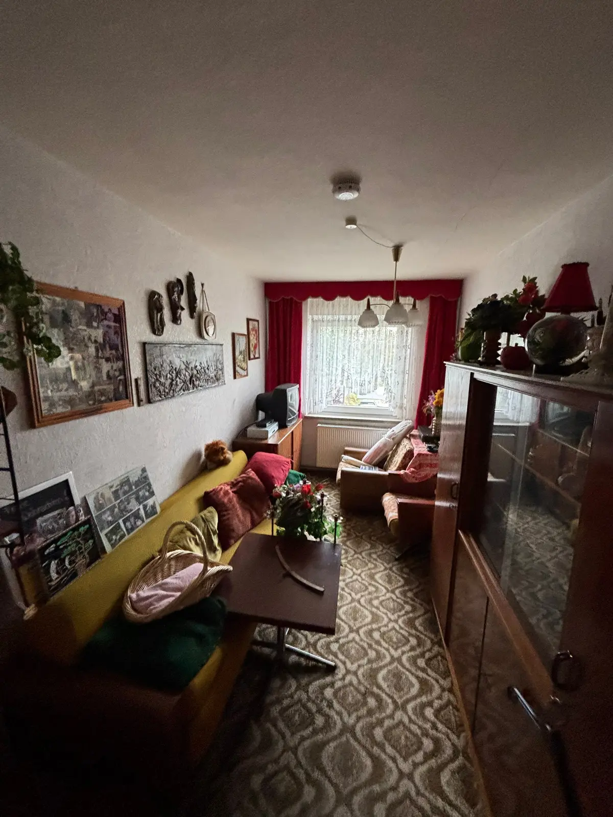 Wohnzimmer mit Sofa, Vitrine, Bildern und Hausrat vor einer Nachlassräumung