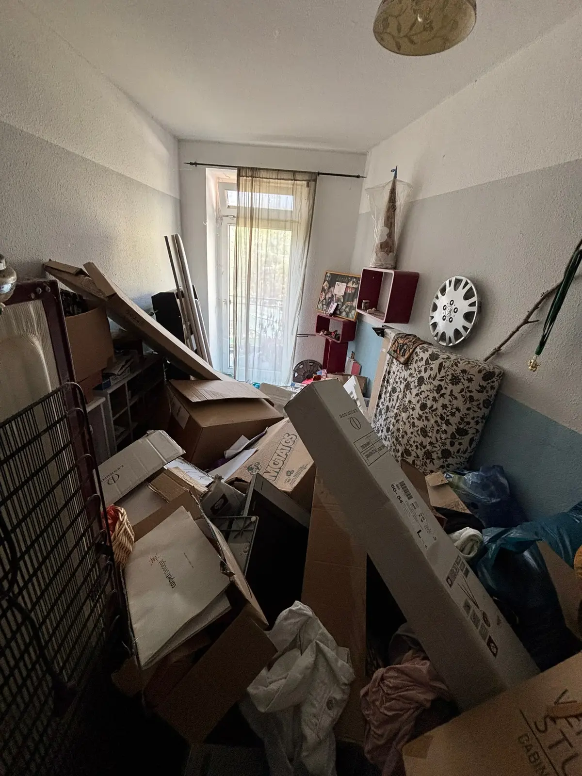 Kleines Zimmer bis zur Balkontür mit Kartons, Säcken und Möbelteilen vollgestellt, kein freier Boden