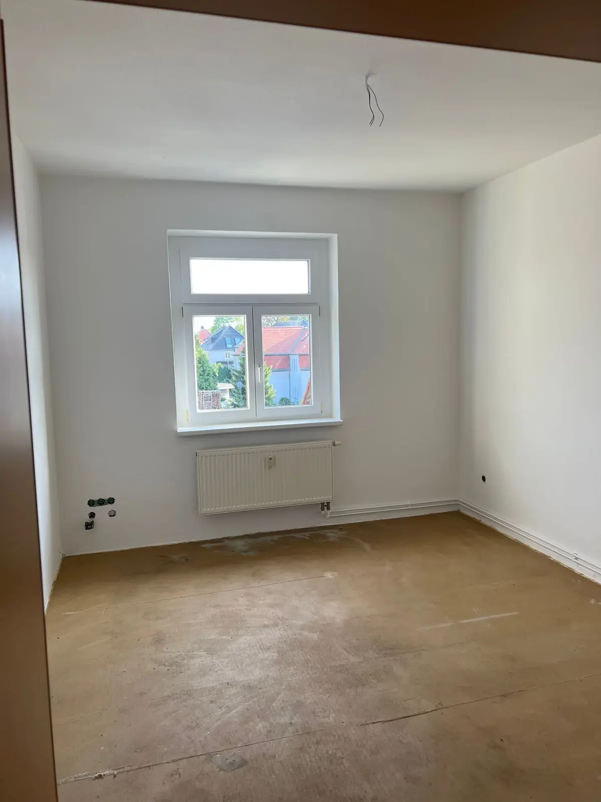 Leergeräumtes helles Zimmer nach Räumung und Entsorgung: Balkontür und Fenster, freier Boden