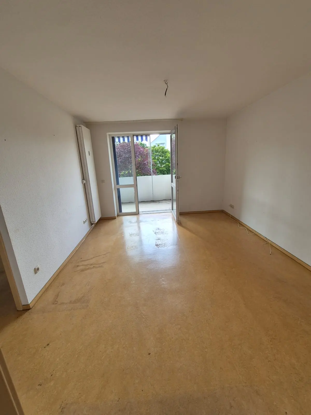 Leergeräumter Wohnraum nach der Auflösung: offene Balkontür, freier Boden, nichts steht mehr im Raum
