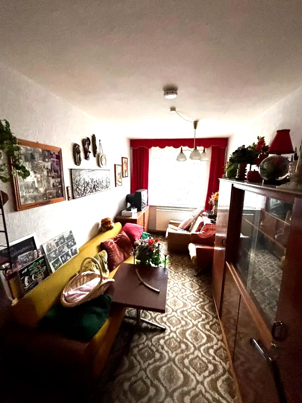 Voll möbliertes Wohnzimmer mit Sofa, Schrankwand, Bildern und Kisten vor der Räumung.